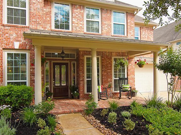 A quaint covered porch is surrounded by lovely landscaping.