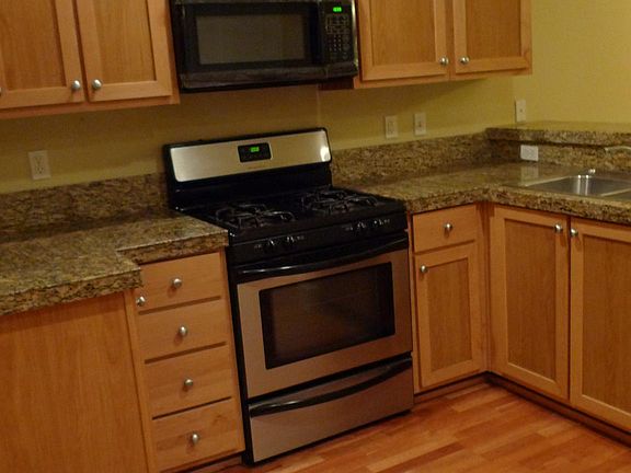 Kitchen with hardwood floor, granite countertop, gas stove and plenty of cabinets spaces