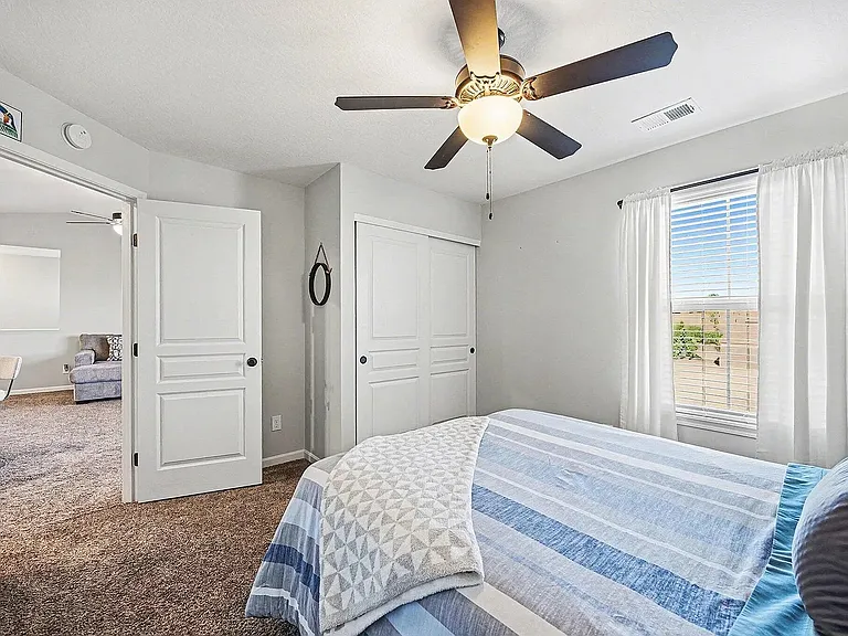 Bright and comfortable bedroom featuring spacious closet, soft carpeting, and plenty of natural light.
