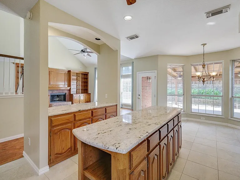 Kitchen island with granite-style countertop, wood cabinetry, and integrated shelving