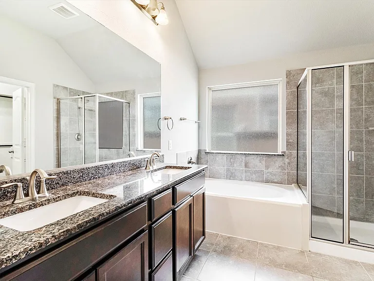 Bathroom featuring a dual vanity with granite-finish countertop, dark wood-finish cabinetry, and brushed nickel fixtures