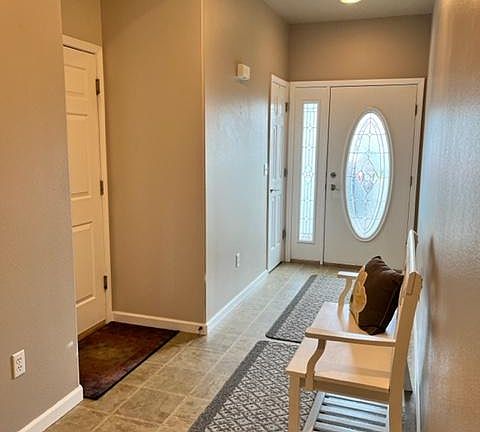 There is a coat closet next to the front door. The door to the garage is visible in this photo.