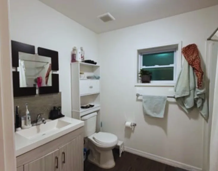 Spacious, spotless bathroom with shower, sink, toilet, and vanity cabinet.