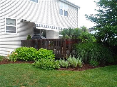 This shows the deck with a remove awning with perennials planted and freshly stained deck