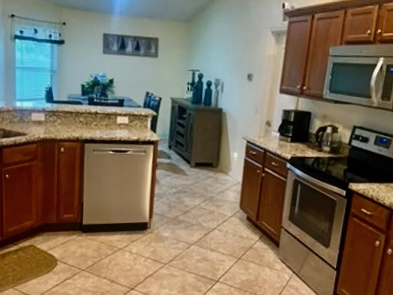 Spacious kitchen with granite counters, ample cabinetry, stainless appliances, and an open layout connected to the dining are