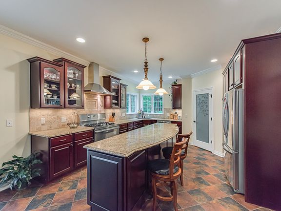 The kitchen is truly a cook's delight with upscale stainless appliances, walk-in pantry, large island, granite counters, cherry cabinetry, tile backsplash and flooring.    