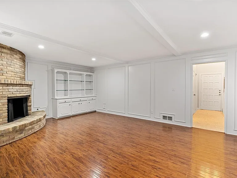 Large living room with built-in storage, gleaming floors and neutral paint.