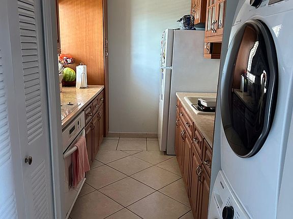 Kitchen with refrigerator, oven, cooktop, washer & dryer, microwave.