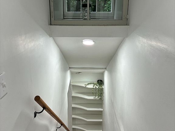 Clean interior stairwell with handrail, overhead lighting, and a large window bringing in natural views.