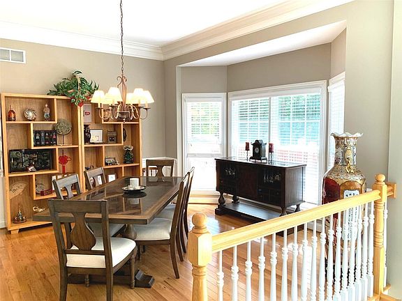 Formal dining room features a bay window, crown molding, hardwood floors and open staircase to the lower level,