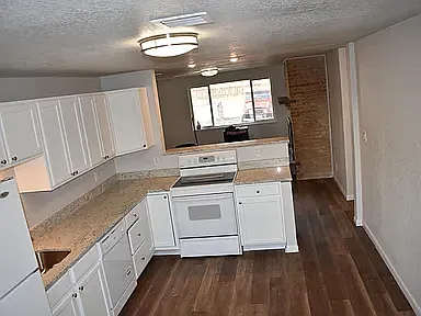 Top unit/ floor kitchen looks into living room with wood-burning fireplace