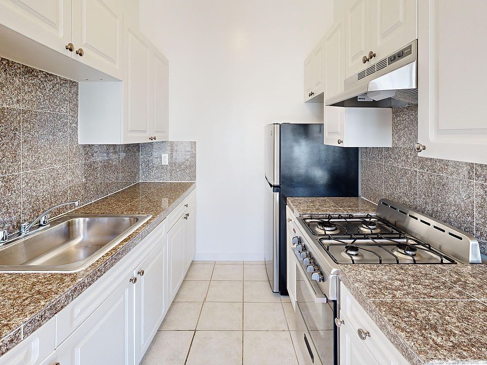 Kitchen with cabinets, refrigerator, stove, range hood, and sink