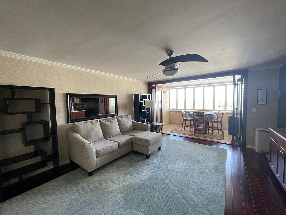 Large living area and lanai with plantation shutters. Wall mounted surfboard rack on lanai wall