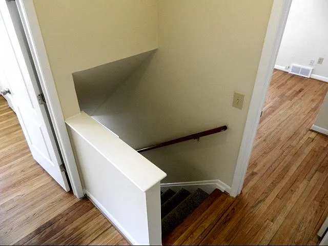 Upstairs with two bedrooms, central stair, hardwood floors.
