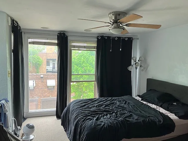 Spacious bedroom with ceiling fan and large windows