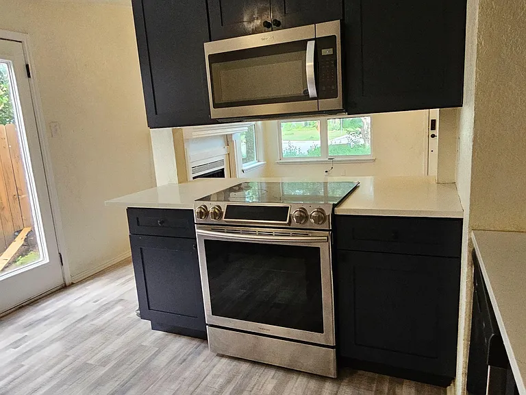 Updated kitchen featuring shaker cabinetry, quartz-style counters, and a stainless range with built-in microwave.