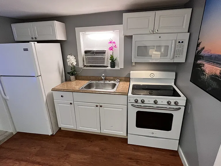 Full kitchen with refrigerator, glass top range, and microwave.