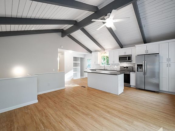 Updated bright & open concept kitchen with quartz counter tops, stainless appliances & vaulted ceilings