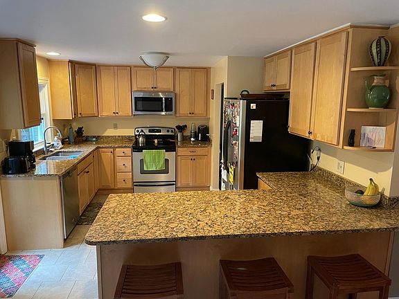 Coming in from sunroom. View is standing in dining room. Kitchen with counter, granite countertops. Glass door seen on left goes to yard.