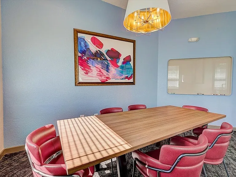 Hold productive meetings in a private room featuring a large table, vibrant decor, and a whiteboard at The Preserve Murfreesboro.
