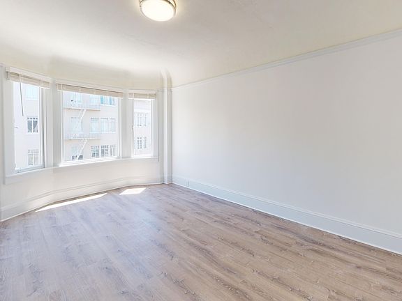 Sunlit room with a large window and wood-like flooring
