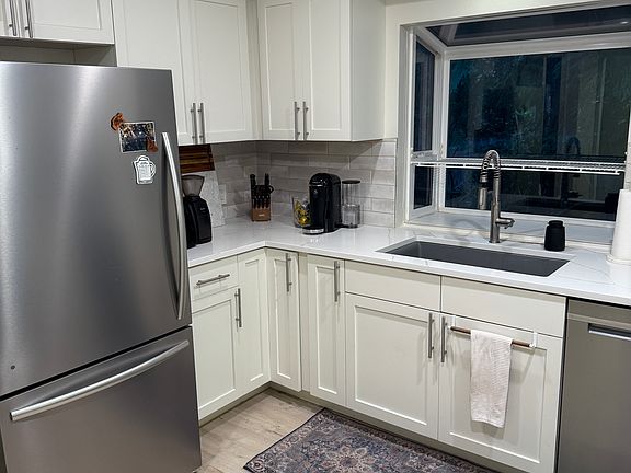 Kitchen (Sink + Window): Updated kitchen with crisp white cabinetry, quartz-style counters, and a large sink overlooking the yard.