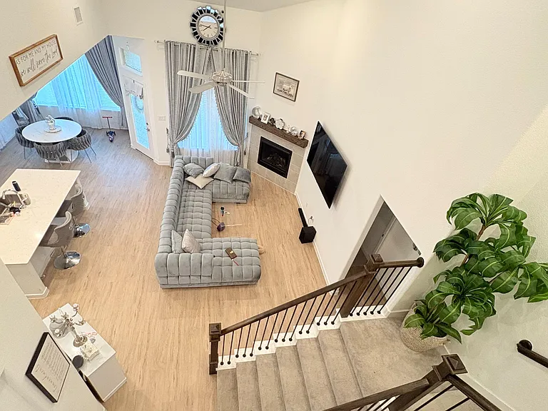 Open-concept living area with high ceilings, large windows, fireplace, and seating zone flowing to a dine-in kitchen bar.