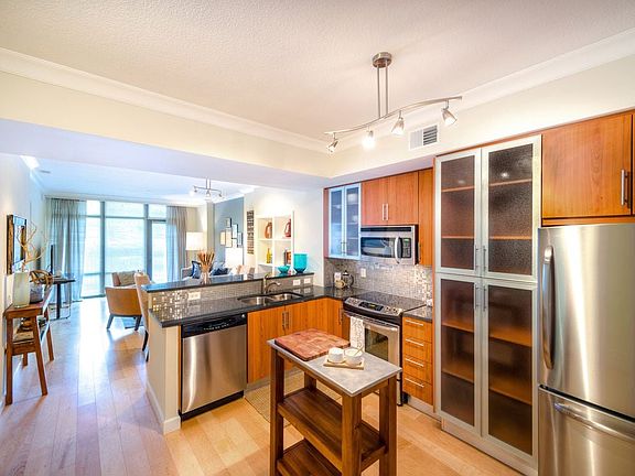 Kitchen with granite countertop, stainless steel appliances, designer backsplash, hard surface flooring and floor to ceiling windows