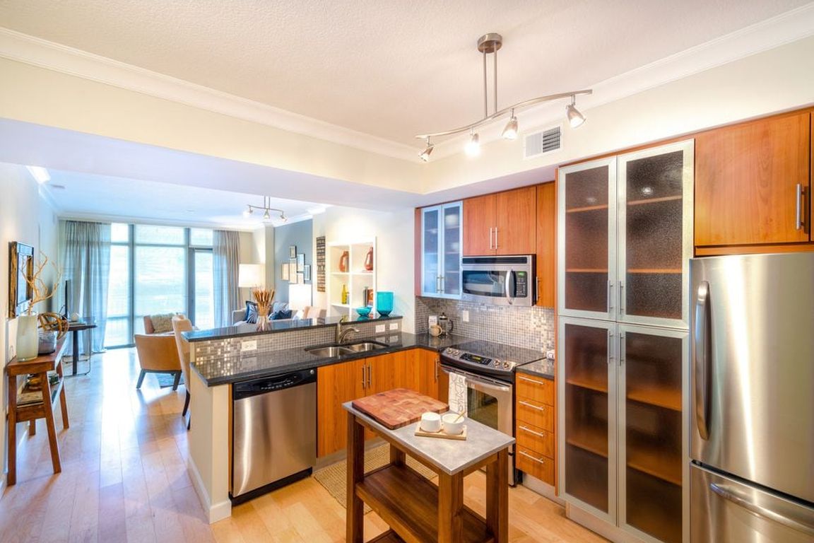 Kitchen with granite countertop, stainless steel appliances, designer backsplash, hard surface flooring and floor to ceiling windows