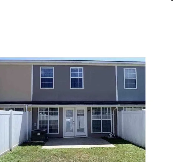 Back yard with white privacy fence and concrete patio; partially covered area for entertaining