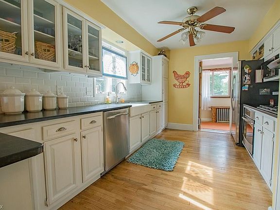 The updated Kitchen features a tile backsplash, soapstone counters, farmhouse sink, painted cabinetry, and hardwood floors.