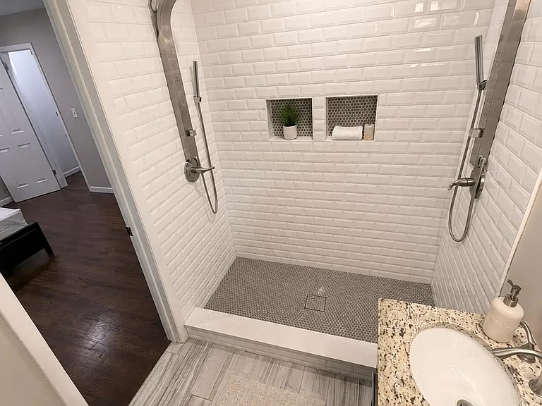 Walk-in tiled shower with dual showerheads, built-in niches, and a granite vanity with undermount sink for easy daily use.