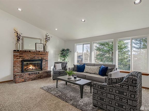 You'll love the soaring ceilings and wall of windows in the spacious living room. The wood burning fireplace is a cozy focal point. 