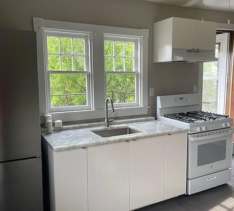 Kitchen with beautiful granite counter tops, white gas stove, and a large stainless steel refrigerator.