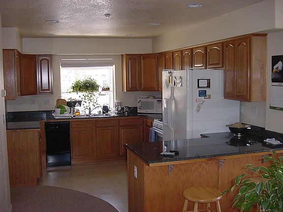Kitchen with oak cabinets, granite countertops, dishwasher, greenhouse window and breakfast bar