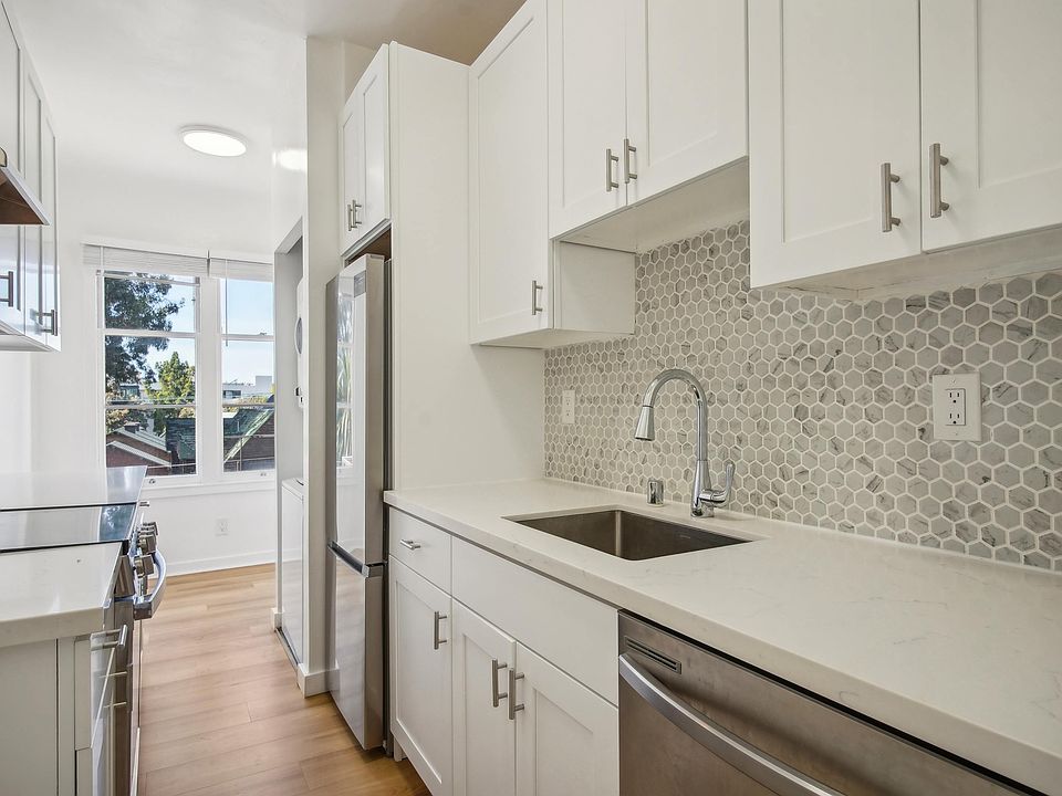 Kitchen with multiple cabinets, refrigerator, stove, range hood, and sink