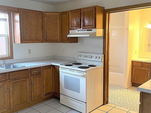 Kitchen has electric stove and extra cabinet storage to the right of the bathroom doorway.