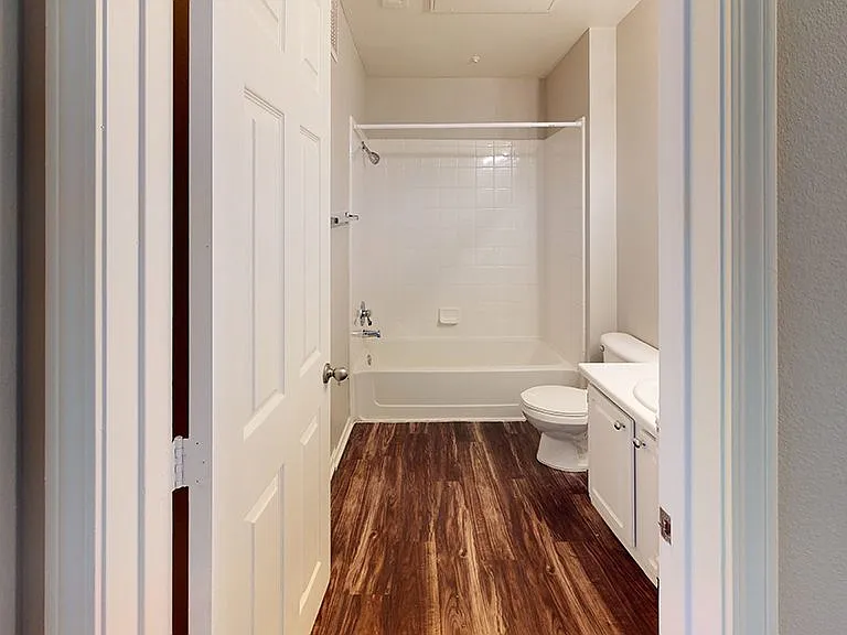 Apartment bathroom with wood-style flooring.