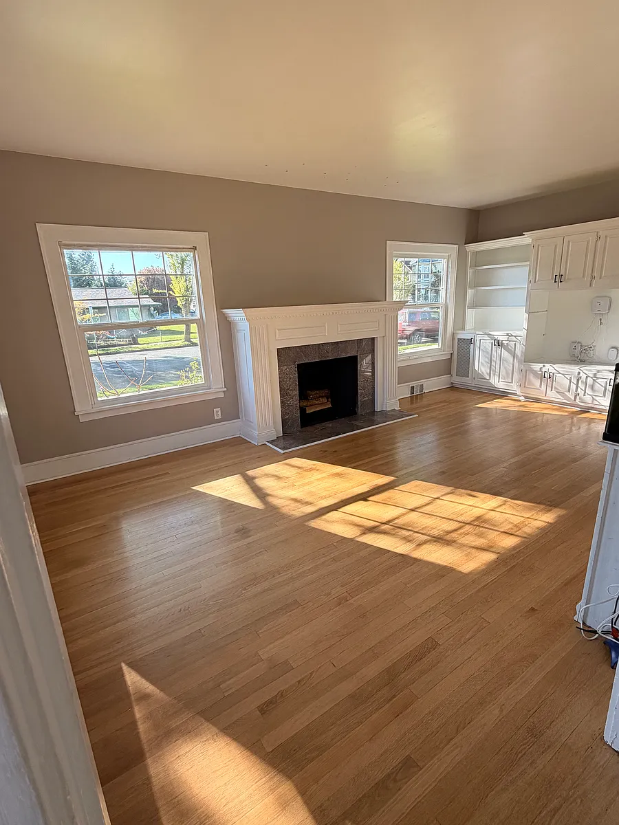 Bright, inviting living room with original hardwoods and a classic wood_burning fireplace. - 903 Park St