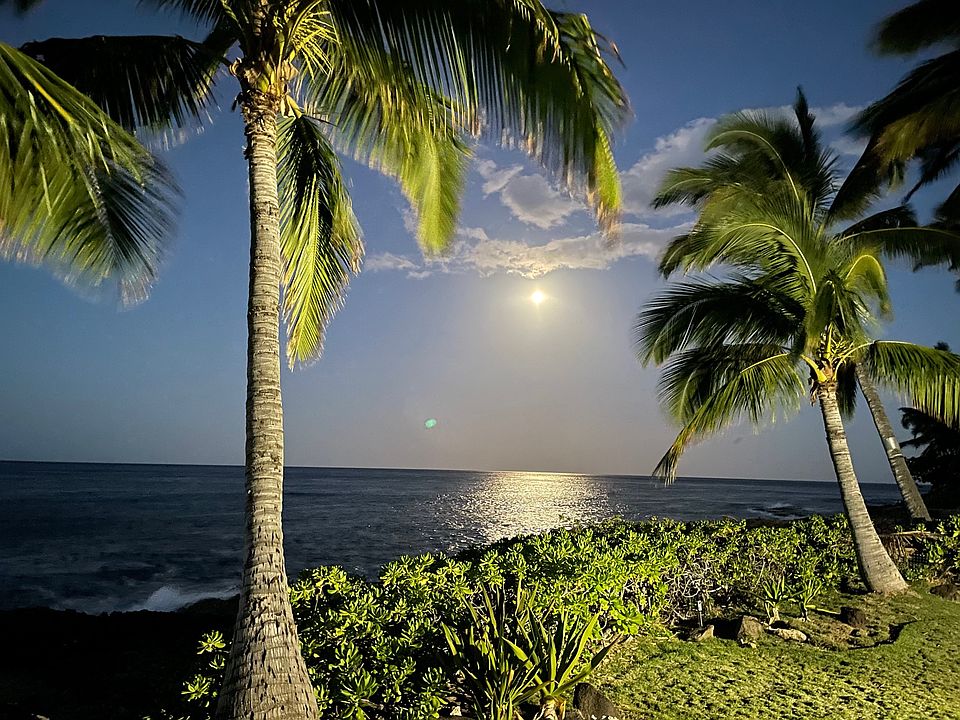 Full moon setting over ocean.