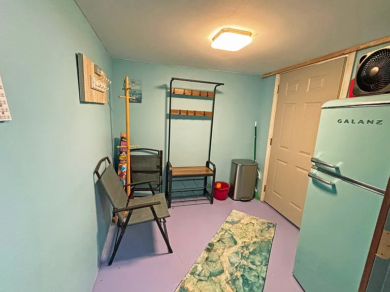 Photo from room looking into entryway with refrigerator and storage