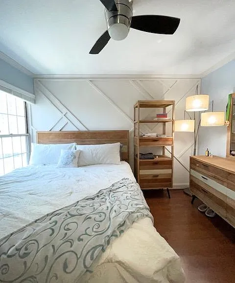 Light filled bedroom with new king bed, nightstand tower, dresser, and chest. Custom done paneling work on wall.
