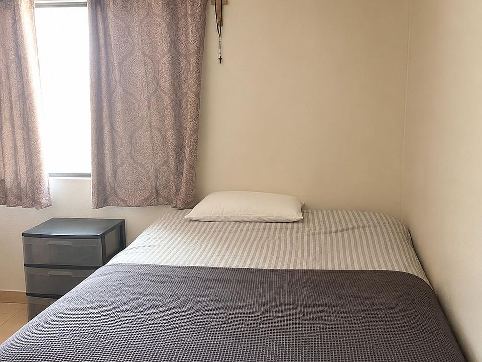 Furnished bedroom with a comfortable bed, bedside storage, and a window with curtains for light control and privacy.