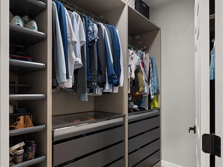 Walk-in closet with built-in shelving, hanging rods, and multiple drawer organizers for streamlined everyday storage.