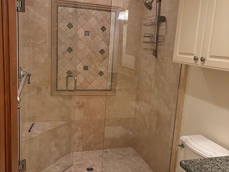 Large shower with custom easy care tiles, ample storage below sink and above toilet