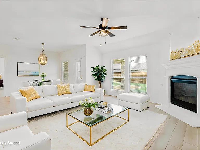 Bright living area featuring wood-finish flooring, a contemporary ceiling fan, and a built-in fireplace with a white mantel