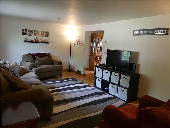 The living room features neutral paint and the warm tones of hardwood flooring.