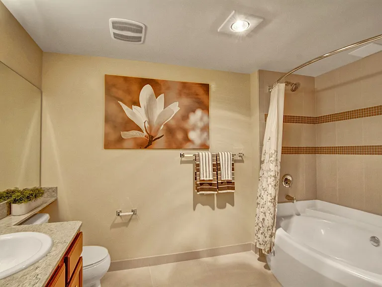 A large bathroom with double sinks, a shower and bathtub combination, and a wide mirror above the sinks