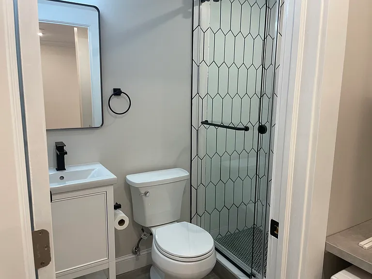 Bathroom with glass shower door and storage cabinets.