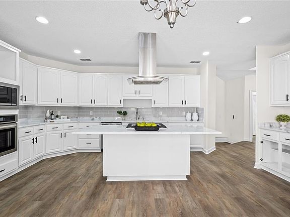 Kitchen featuring stainless steel appliances, island range hood, a center island, and dark wood-type flooring